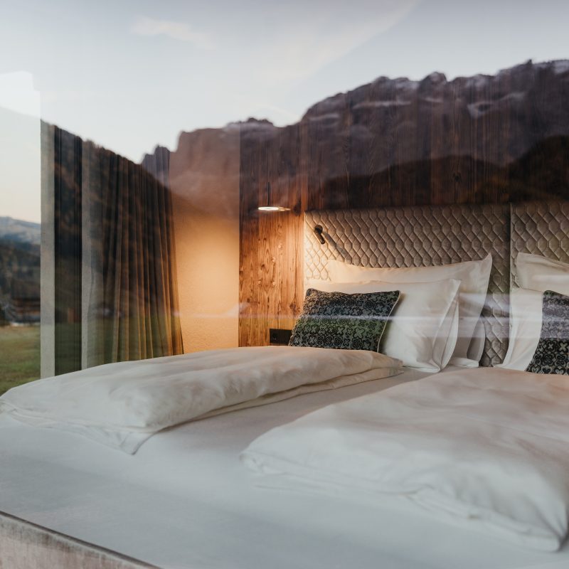 Vista esterna della camera matrimoniale all'Chalet Sasslong con il riflesso del panorama.