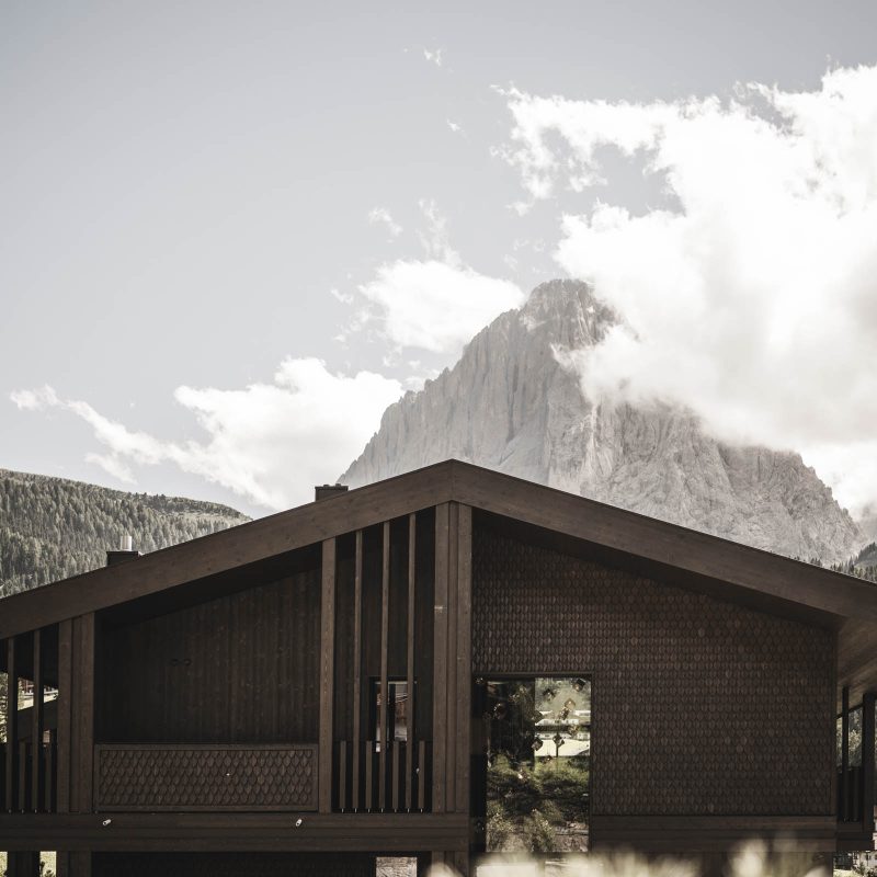 Tetto affascinante dell'Chalet Gardena di Cortina Hospitality, con giochi di legno intarsiato e creativi giochi di vuoti e pieni, unendo l'architettura alla bellezza naturale.