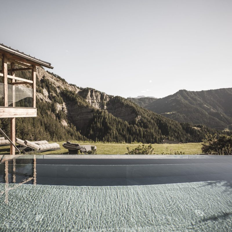 Infinity pool nel giardino paradisiaco dell'Chalet Seceda di Cortina Hospitality, un'esperienza di lusso e serenità senza fine.