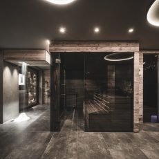 Panorama della zona spa con cascata di neve, sauna e bagno turco nell'Chalet Seceda di Cortina Hospitality, un'oasi invernale di lusso e tranquillità.