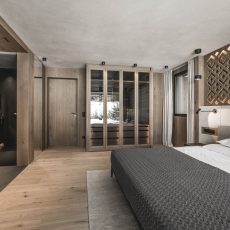 Vista completa della suite all'Chalet Gardena di Cortina Hospitality, con letto matrimoniale, bagno in camera e armadio, simbolo di eleganza e comfort.