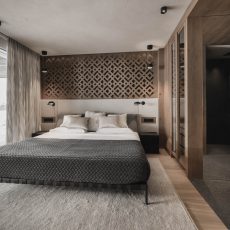 Suite all'Chalet Gardena di Cortina Hospitality, con ampia finestra a tutta altezza e larghezza, creando un'atmosfera luminosa e una vista panoramica.