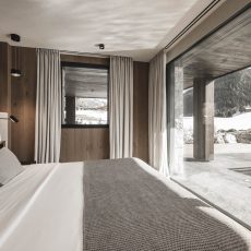 Vista panoramica dalla stanza padronale all'Chalet Gardena di Cortina Hospitality, con infinita porta finestra che svela la piscina e il bellissimo giardino.