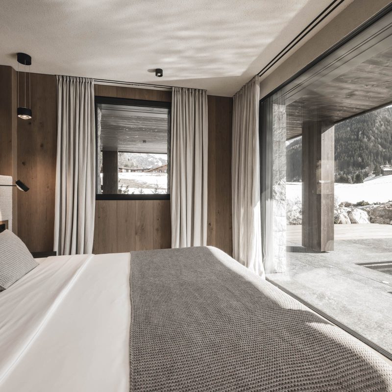 Vista panoramica dalla stanza padronale all'Chalet Gardena di Cortina Hospitality, con infinita porta finestra che svela la piscina e il bellissimo giardino.