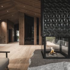 Caminetto a 360 gradi acceso nel living all'Chalet Gardena di Cortina Hospitality, regalando una vista incantevole e un'atmosfera magica.