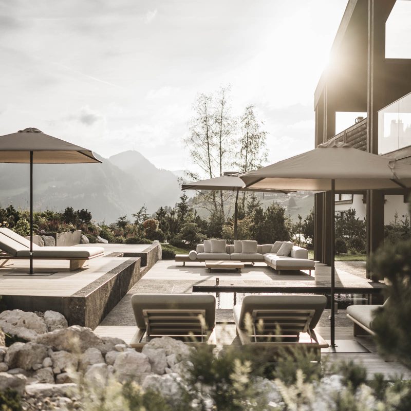 Zona esterna della casa all'Chalet Gardena di Cortina Hospitality, immersa in una luce magica con il giardino perfettamente integrato nel panorama.
