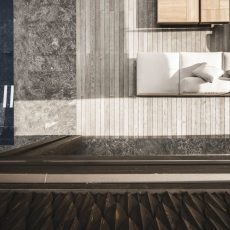 Vista aerea della zona esterna con divano, piscina e deck presso l'Chalet Gardena di Cortina Hospitality, evidenziando l'armonia dei materiali e l'eleganza nell'allestimento esterno.
