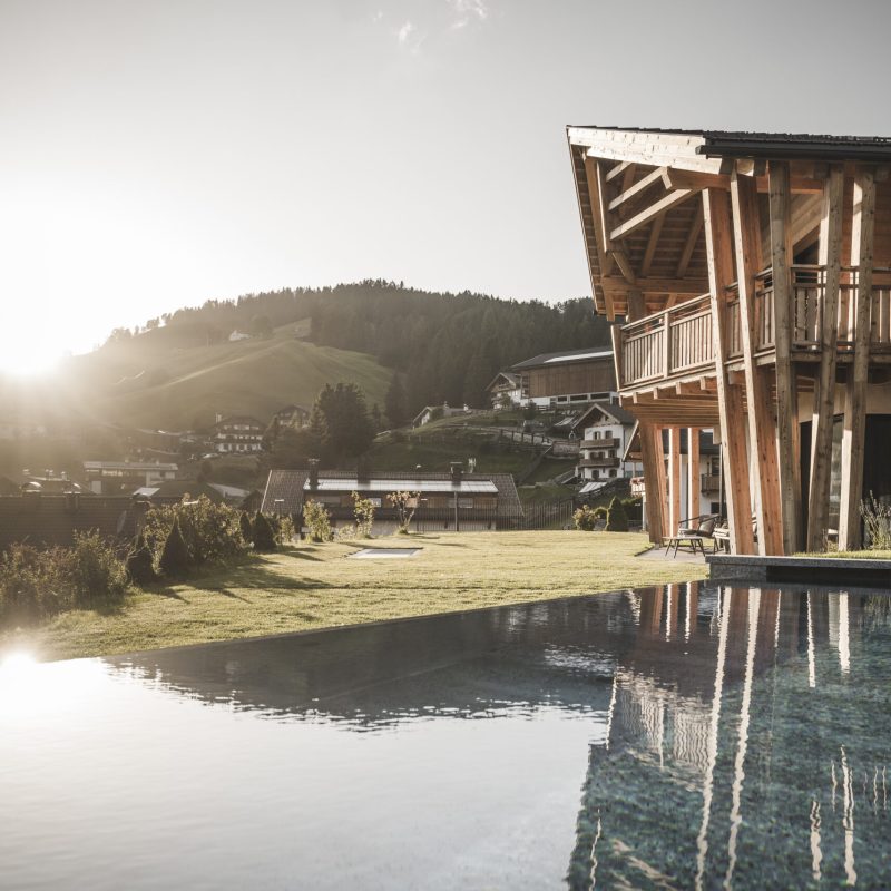 Vista esterna dell'Chalet Sasslong con architettura raffinata, piscina e sfondo delle Dolomiti