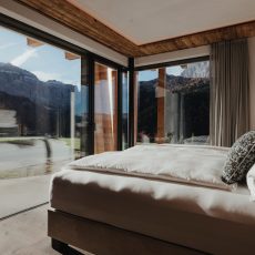 Vista interna della camera matrimoniale all'Chalet Sasslong con le grandi finestre.