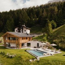Vista grandangolare dell'Chalet Sasslong con giardino, piscina e solarium