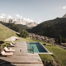 Vista esterna dell'Chalet Sasslong con solarium in legno e piscina panoramica.