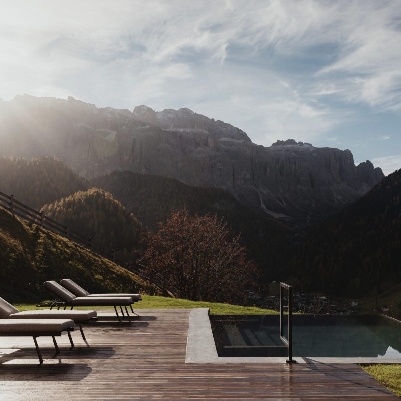 Vista del solarium e della piscina all'Chalet Sasslong con suggestiva panoramica sulle Dolomiti
