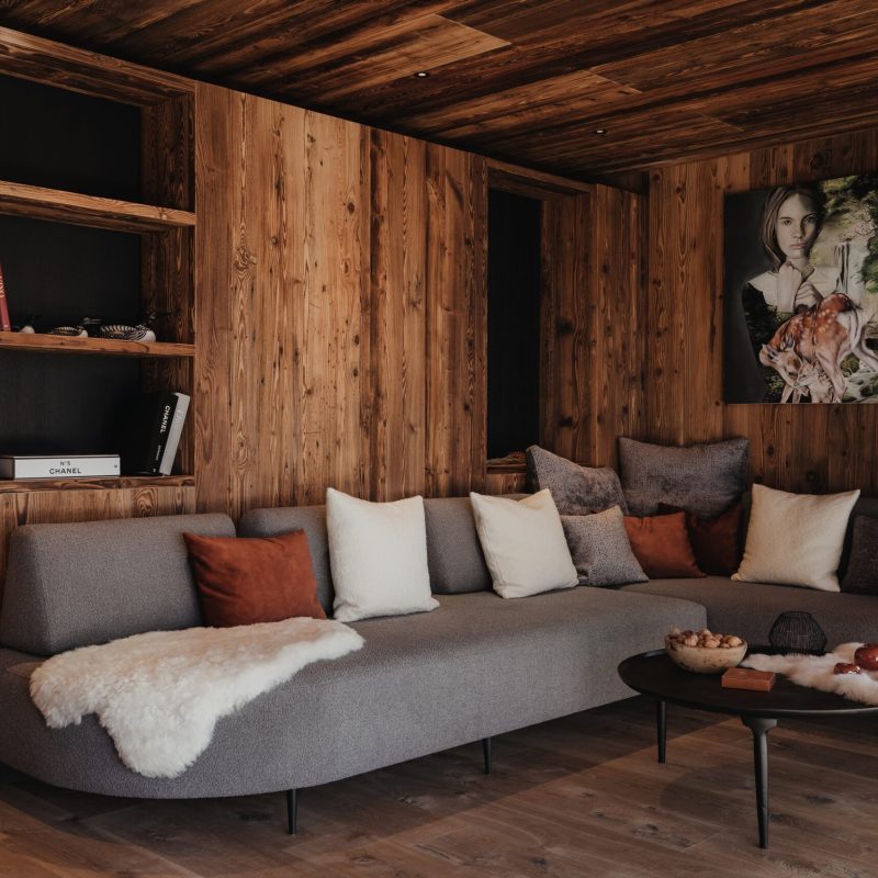 Vista dell'angolo del divano e della libreria in legno all'Chalet Sasslong.