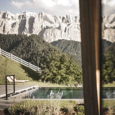 Vista della piscina esterna dell'Chalet Sasslong con riflessi delle maestose montagne.