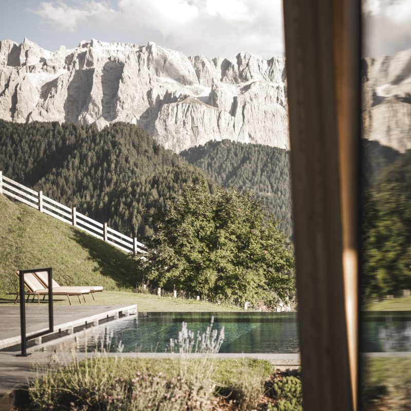 Vista della piscina esterna dell'Chalet Sasslong con riflessi delle maestose montagne.
