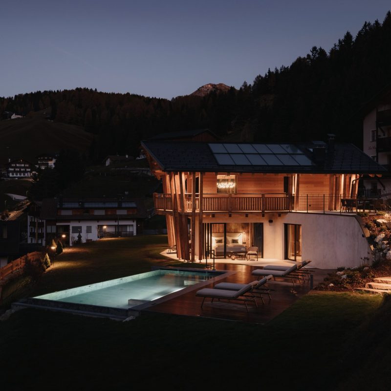 Vista panoramica notturna delle Dolomiti dal Chalet Sasslong immerso nelle luci notturne.